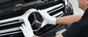 Ein Mitarbeiter von Mercedes-Benz bringt den Stern an einem Auto der C-Klasse an.