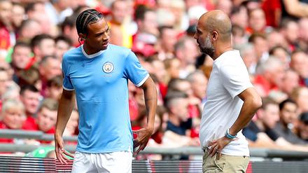 Manchesters Leroy Sane (l) spricht nach seiner Auswechslung mit Trainer Pep Guardiola. 