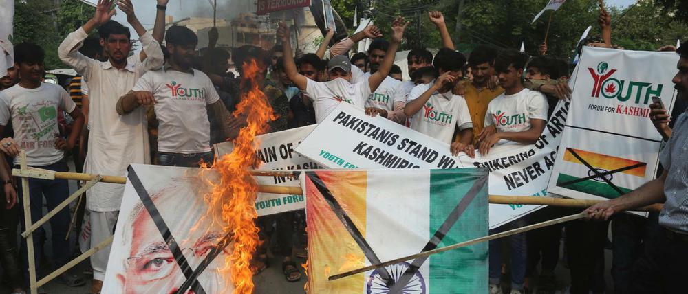 Pakistanische Demonstranten verbrennen bei einer Kundgebung eine Fahne mit dem Bild des indischen Premierministers Modi.