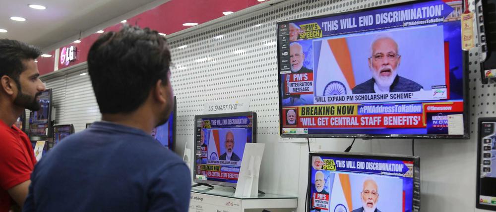 Zwei Inder verfolgen eine Fernsehansprache des indischen Premierministers Narendra Modi in einem Elektronikgeschäft.