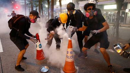 Bei einer Protestkundgebung in Hongkong versuchen Demonstranten, Tränengas-Kartuschen zu löschen.