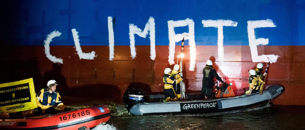 Greenpeace-Aktivisten bemalen auf der Weser das Frachtschiff "Hiroshima Star" mit dem Schriftzug "Climate Crime" (Klimaverbrechen).