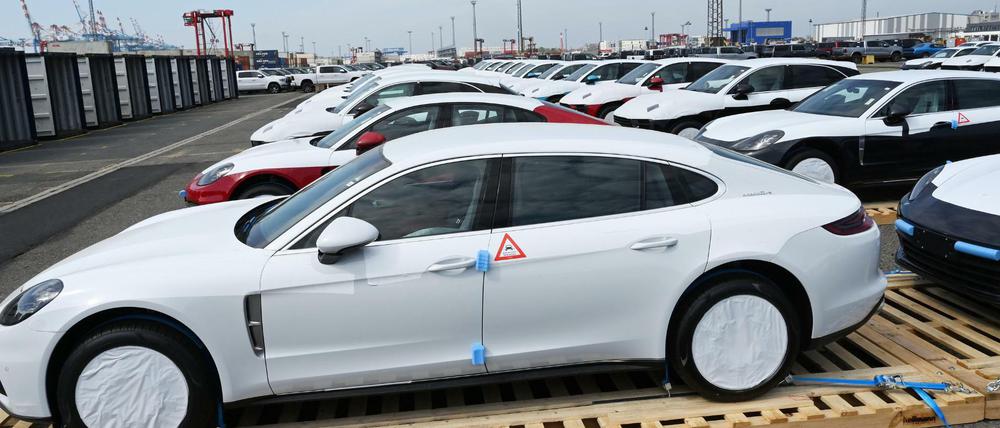 Fahrzeuge von Porsche stehen vor ihrer Verladung in Container in Bremerhaven auf Paletten.