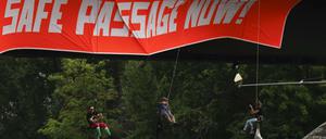 Demonstranten seilen sich von einer Brücke über dem Main ab.