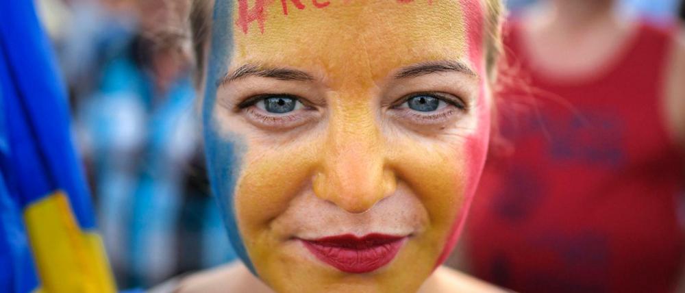Eine Frau hat ihr Gesicht in den rumänischen Nationalfarben geschminkt, auf ihrer Stirn steht der Hashtag #Widerstand.