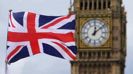 Großbritannien, London: Eine britische Fahne weht vor dem berühmten Uhrturm Big Ben.