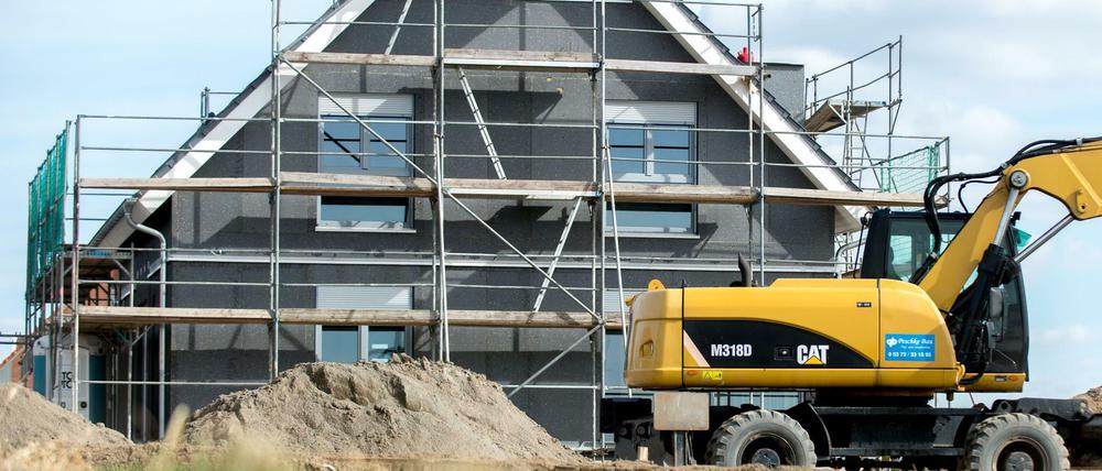 Ein eingerüsteter Rohbau eines Einfamilienhauses steht in einem Neubaugebiet (Symbolbild).