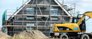 Ein eingerüsteter Rohbau eines Einfamilienhauses steht in einem Neubaugebiet (Symbolbild).