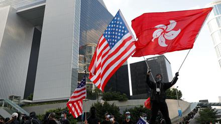 Ein Demonstrant schwenkt eine Flagge von Hongkong und eine Flagge der USA im Rahmen des Protestes. 