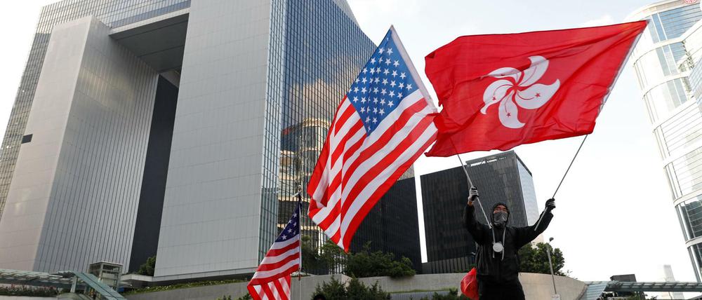 Ein Demonstrant schwenkt eine Flagge von Hongkong und eine Flagge der USA im Rahmen des Protestes. 