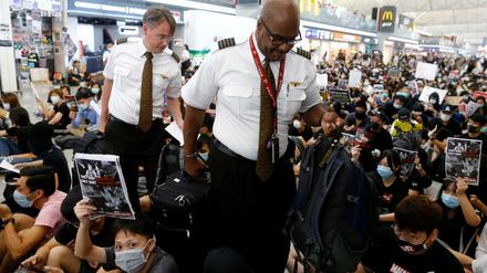 Angestellte einer Airline bahnen sich einen Weg durch die Demonstranten am Flughafen Hongkong.