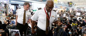 Angestellte einer Airline bahnen sich einen Weg durch die Demonstranten am Flughafen Hongkong.