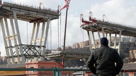 Ein Mann beobachtet das Absenken eines Abschnitts der Morandi-Brücke.