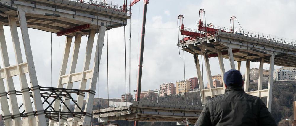 Ein Mann beobachtet das Absenken eines Abschnitts der Morandi-Brücke. 