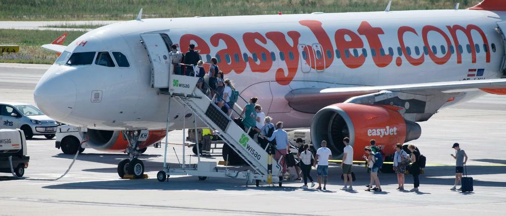 26.07.2019, Berlin: Reisende in sommerlicher Kleidung besteigen bei Temperaturen um die 30 Grad eine Maschine der Fluglinie Easyjet am Flughafen Schönefeld. Foto: Paul Zinken/dpa +++ dpa-Bildfunk +++