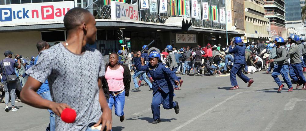 Bereitschaftspolizisten gehen in Harare gewaltsam gegen Demonstranten vor.