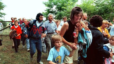 DDR-Flüchtlinge mit ihren Kindern gehen durch das geöffnete Grenztor von Ungarn aus nach Österreich. 