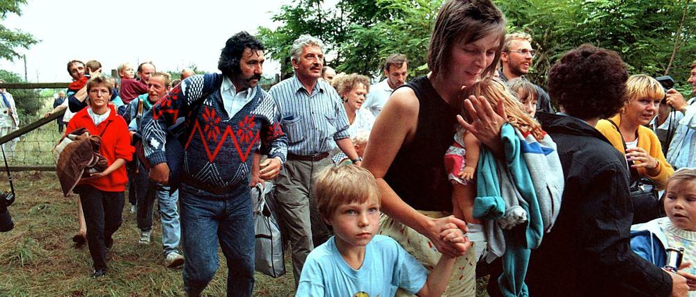 DDR-Flüchtlinge mit ihren Kindern gehen durch das geöffnete Grenztor von Ungarn aus nach Österreich.