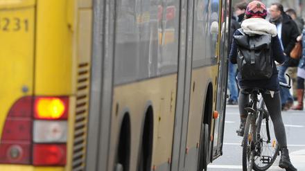 Ein Radfahrer steht auf einer Busspur an einer Kreuzung, hinter ihm ein Bus der BVG