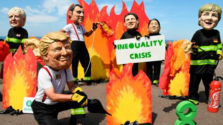 Demonstranten tragen Masken der G-7-Teilnehmer.
