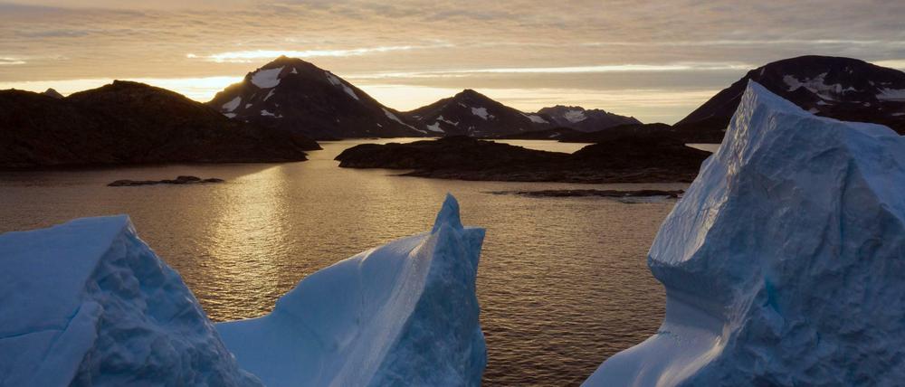 Eisberge treiben bei Sonnenaufgang in der Nähe von Kulusuk auf dem Wasser.