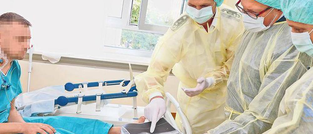 Am Bett eines Patienten zeigt Oberstabsarzt Denis Vogt dem ukrainischen Botschafter Andrij Melnyk ein Röntgenbild.