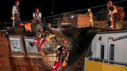 Feuerwehrleute entfernen auf dem Haus in Gesundbrunnen Dachpappe, welche durch ein Unwetter abgelöst wurde.