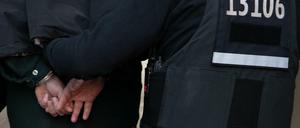 Berlin: Polizeibeamte führen mit Handschellen einen festgenommenen Mann nach einer Razzia in einem Wohnhaus in Tempelhof ab.