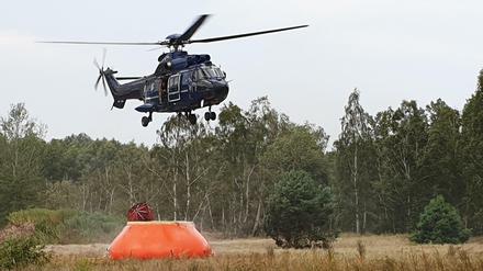 Ein Hubschrauber nimmt Wasser zum Löschen auf. In Brandenburg sind erneut Brände auf ehemaligen Truppenübungsplätzen ausgebrochen.