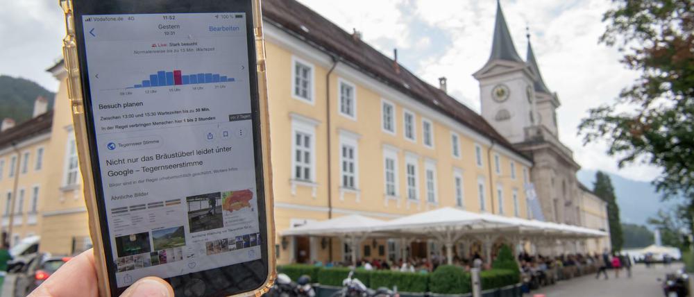Ein Smartphone mit einer Google-Anzeige wird vor das Bräustüberl am Tegernsee gehalten.