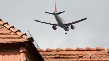 Ein Flieger der Fluggesellschaft Easyjet im Anflug dicht über den Hausdächern. 