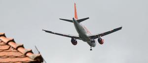 Ein Flieger der Fluggesellschaft Easyjet im Anflug dicht über den Hausdächern.