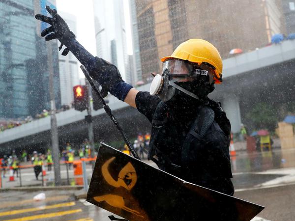 Ein Demonstrant in Hongkong, während er von einer Wasserkanone der Polizei beschossen wird.