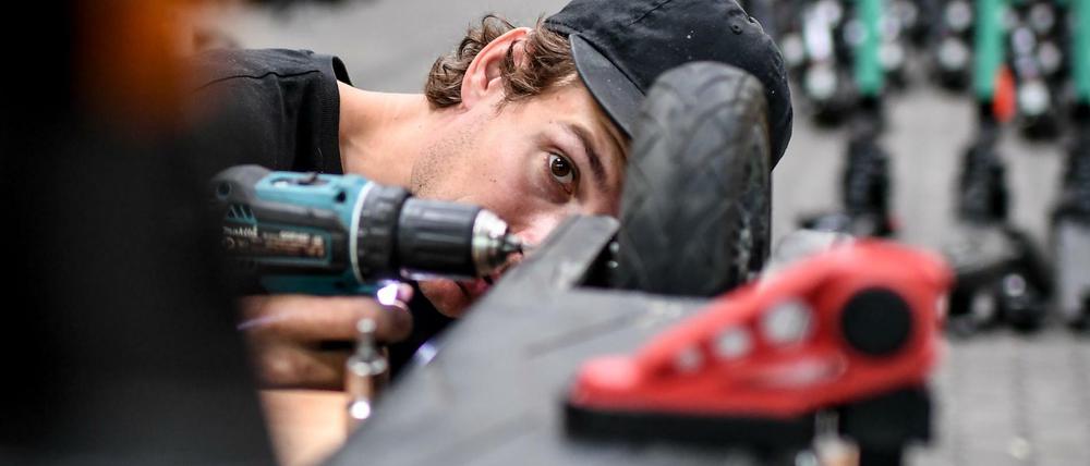Florian Väth, Mechaniker baut ein Rad an einem E-Tretroller des Anbieters Tier an.