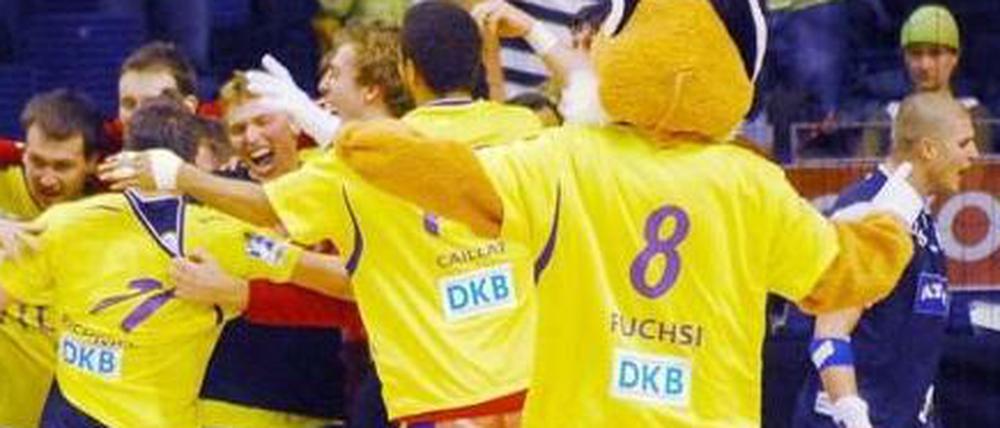 Maskottchen Fuchsi jubelt mit den Handballern der Reinickendorfer Füchse.