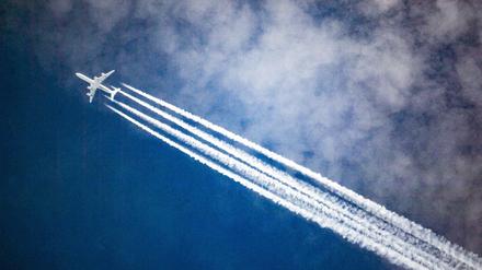 Ein Flugzeug zieht Kondensstreifen hinter sich her, während es durch die Wolken fliegt.