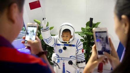 Ein Junge lässt sich in Peking in einer Nachbildung eines chinesischen Astronautenanzugs fotografieren.