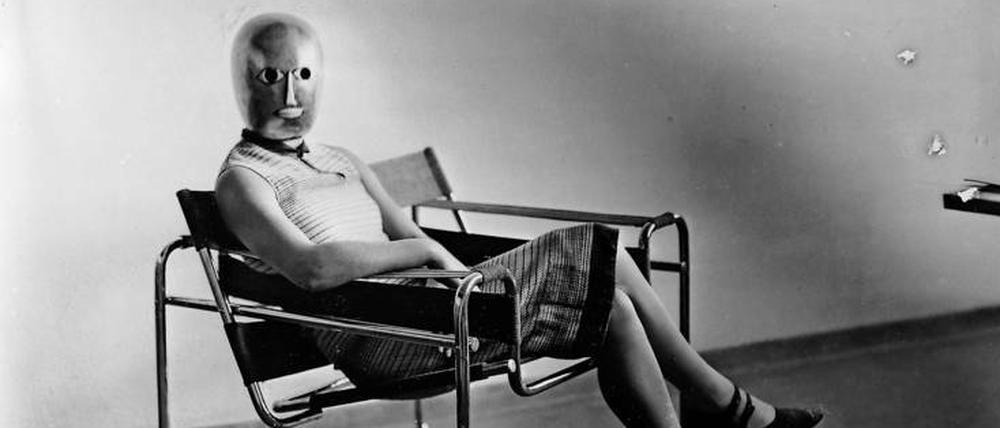 Wer blickt hier so stumm im Studio herum? Die Aufnahme einer Sitzenden mit Bühnenmaske von Oskar Schlemmer im Stahlrohrsessel von Marcel Breuer entstand um 1926.