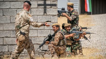 Ein Bundeswehrsoldat (l.) bildet kurdischer Kämpfer im Nordirak aus.