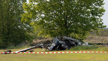 Brandenburg, Zehdenick: Der Wrack eines Kleinflugzeugs liegt nach einem Absturz auf einem Feld zwischen dem Ortsteil Badingen und Gransee hinter einem Absperrband der Polizei. 