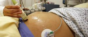 Illustration: Eine Hebamme führt eine Ultraschall-Untersuchung durch. 