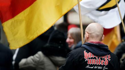 Ein Demonstrant steht in Köln zwischen Deutschlandfahnen.