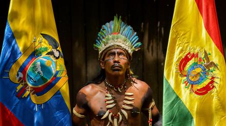 Ein junger Kolumbianer vom indigenen Volk der Tikuna zwischen den Flaggen Ecuadors und Boliviens. 