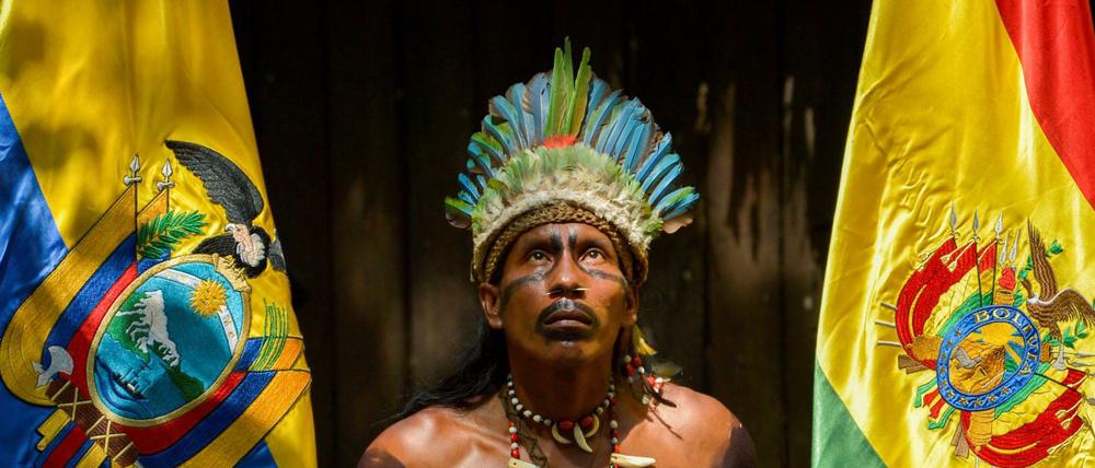 Ein junger Kolumbianer vom indigenen Volk der Tikuna zwischen den Flaggen Ecuadors und Boliviens. 