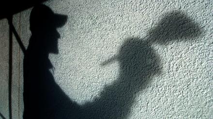 Der Schatten eines Malers ist auf einer Hauswand. Gewerkschaften wollen einen besseren Schutz der Arbeiter.