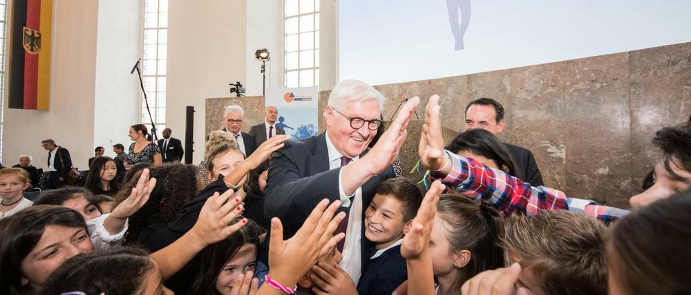 Frank-Walter Steinmeier klatscht Schüler ab, die ihm die Hände entgegenstrecken.