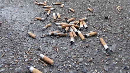 Zigarettenstummel auf asphaltiertem Gehweg.