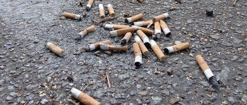 Zigarettenstummel auf asphaltiertem Gehweg.