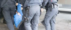 Polizisten schleppen eine Demonstrantin weg.