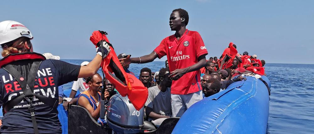 Eine Helferin des Rettungsschiffs "Eleonore" gibt Westen an Flüchtlinge auf einem Boot aus.